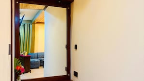 Un pasillo con techo de madera y un espejo grande que refleja una habitación con un sofá azul y una cortina verde.