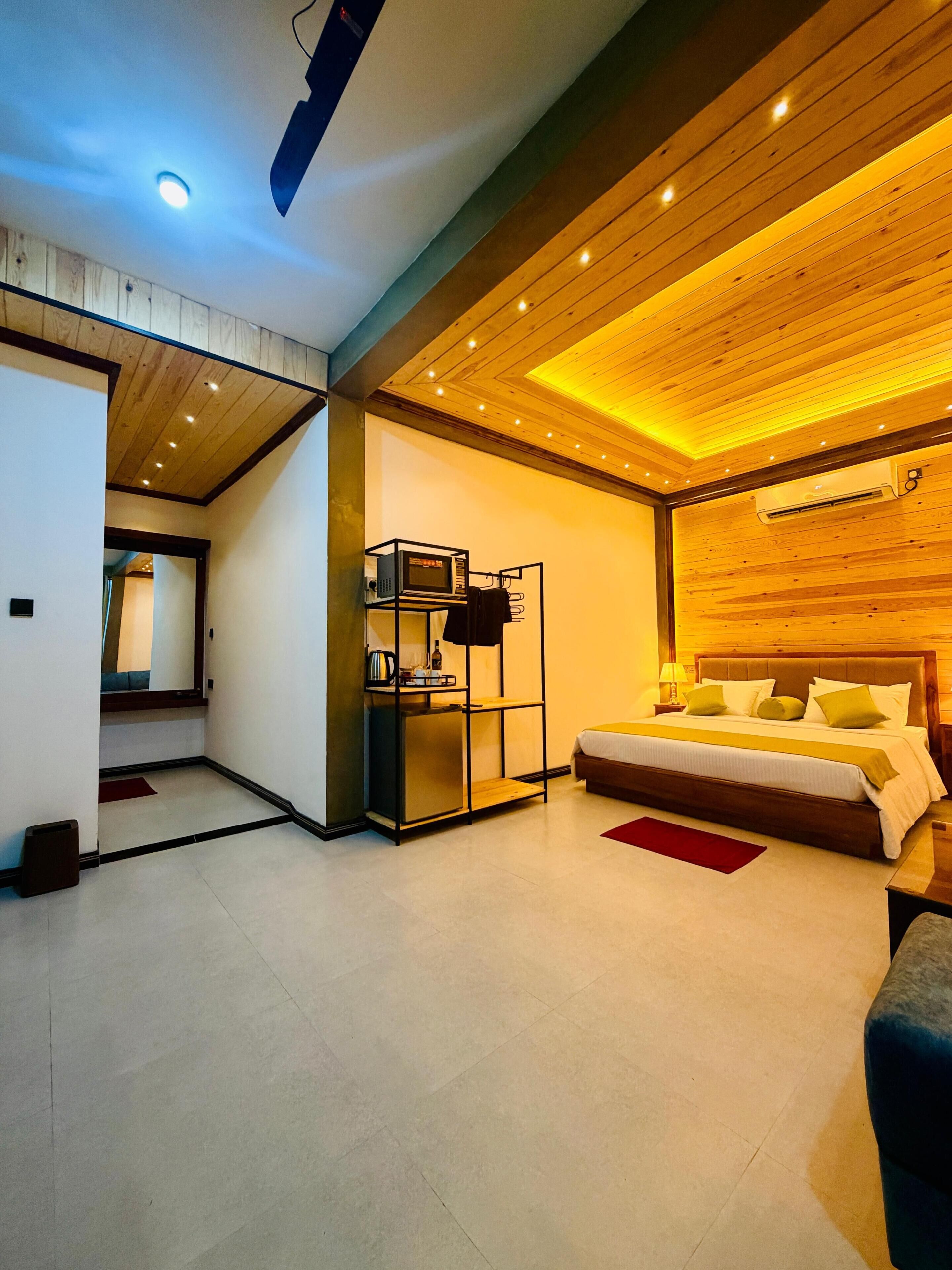 Una habitación de hotel moderna con cama, mesita de noche y aire acondicionado integrado.