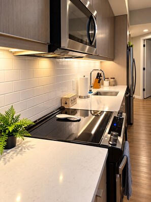 A modern kitchen with a stainless steel range, a built-in oven, a microwave, and a sink. - Downtown Raleigh - Sweeping City Views - Luxury High Floor Unit 2 Bedroom 2 bath (Raleigh)