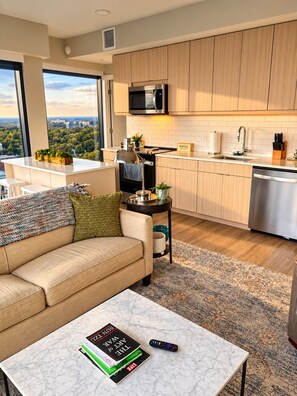 A modern living room with a sofa, coffee table, and a view of the city. - Downtown Raleigh - Sweeping City Views - Luxury High Floor Unit 2 Bedroom 2 bath (Raleigh)