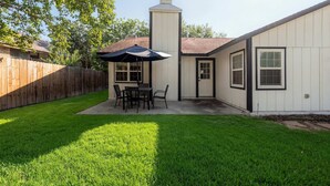 Un jardin avec une terrasse, une clôture en bois et une pelouse.
