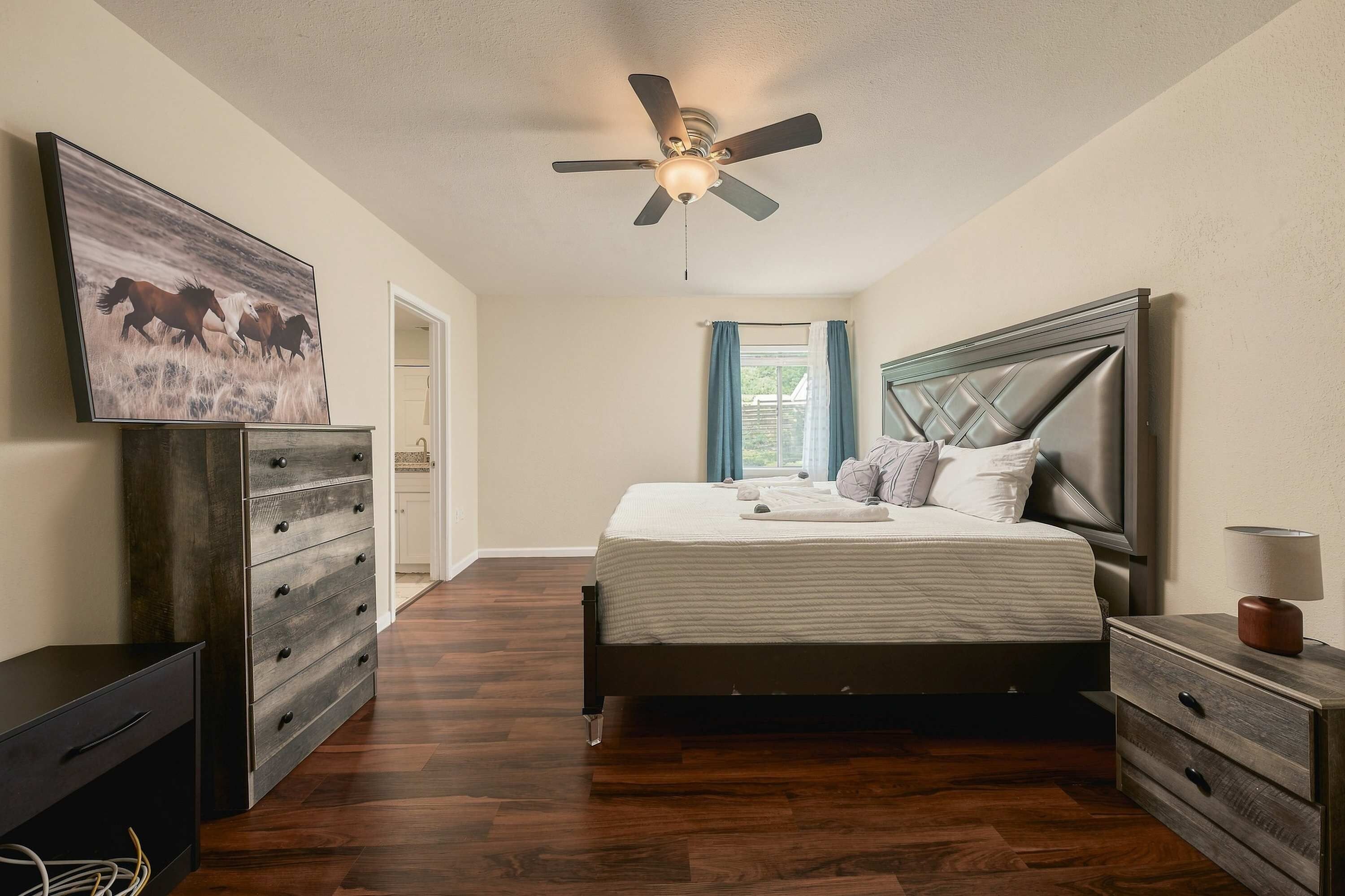 Ein Schlafzimmer mit einem Bett, einer Kommode, einem Deckenventilator und einem Gemälde an der Wand.
