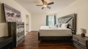 Une chambre à coucher avec un lit, une commode, un ventilateur de plafond et un tableau accroché au mur.