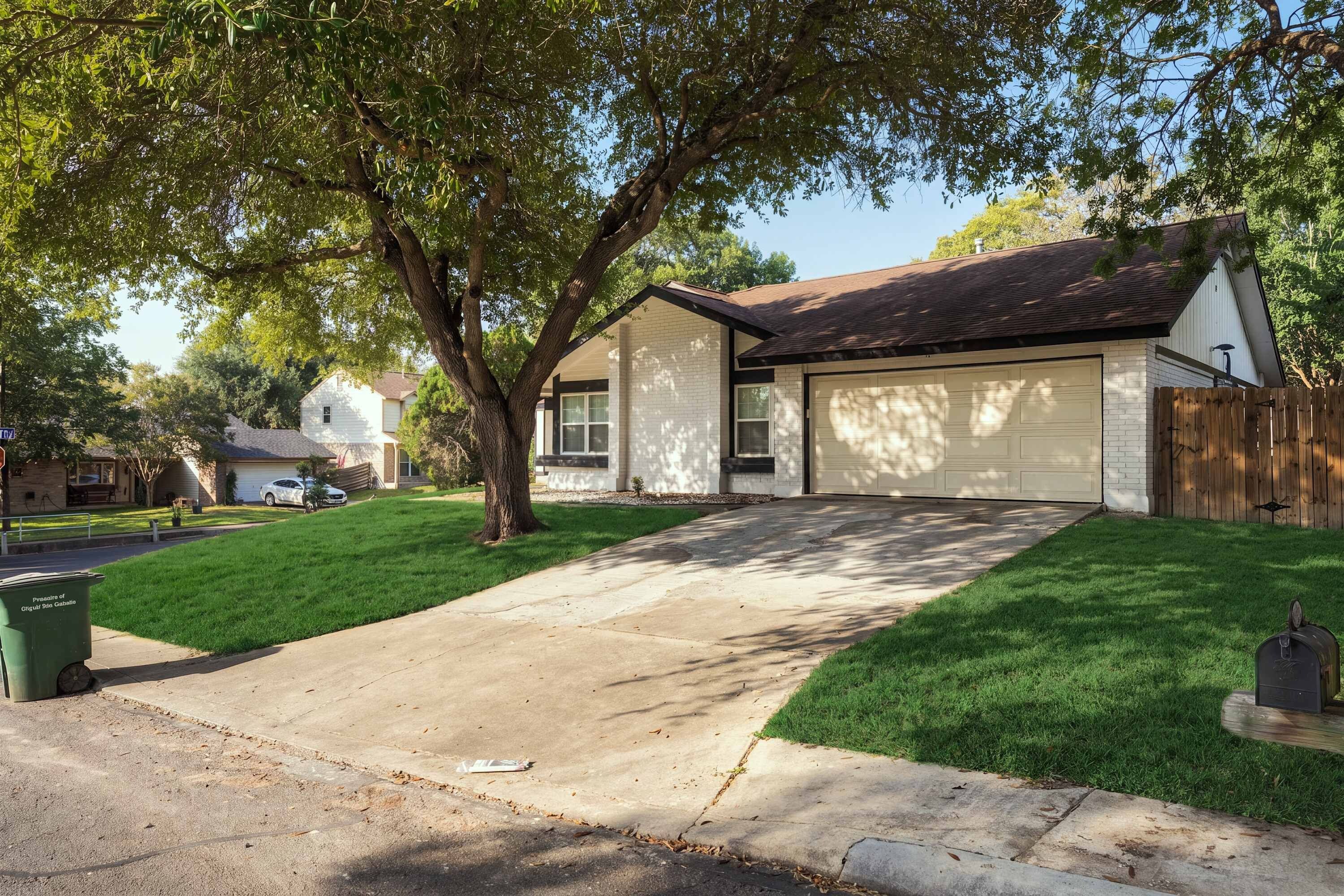 A residential house with a garage, a driveway, and a well-maintained lawn.
