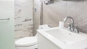 Moderni kylpyhuone, jossa on wc, pesuallas ja suihkutila.
