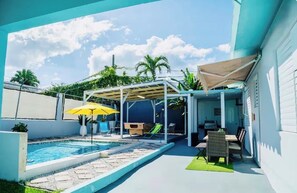 Ein Garten mit Schwimmbad, Gartenmöbeln und einer überdachten Sitzgelegenheit.