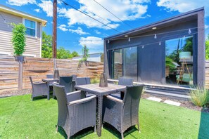 A modern outdoor patio with wicker furniture and a glass door leading to a covered area. - The Cowtown Cottage - 3-bedroom/3-bath house near Magnolia in Fort Worth (Fort Worth)