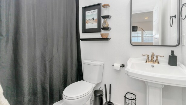 Ein Badezimmer mit Toilette, Waschbecken, Spiegel und einem gerahmten Bild an der Wand.