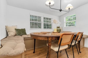 A dining area with a round wooden table, four chairs, and a bench seating area. - The Cowtown Cottage - 3-bedroom/3-bath house near Magnolia in Fort Worth (Fort Worth)