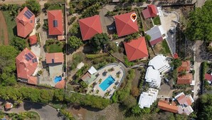 An aerial view of a residential area with multiple houses, a swimming pool, and solar panels on some roofs. - Resort Pool and Sunset Views: 2BR in Playa del Coco (Playa del Coco)