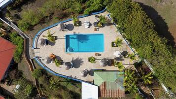 An aerial view of a swimming pool surrounded by palm trees and outdoor seating.