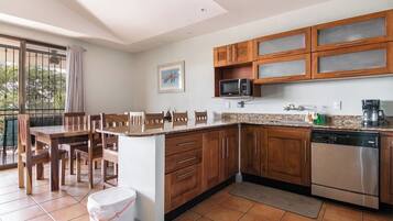 A kitchen with wooden cabinets, a microwave, a dishwasher, and a dining area with chairs and a table.