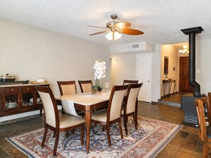 A dining area with a wooden table, chairs, a ceiling fan, and a patterned rug. - Peaceful Albuquerque Stay - Spacious & Welcoming (Albuquerque)