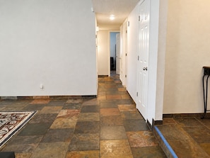 A hallway with patterned stone flooring, white walls, and a door on the right. - Peaceful Albuquerque Stay - Spacious & Welcoming (Albuquerque)