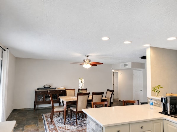 A kitchen with a dining area, a ceiling fan, recessed lighting, and a water dispenser.