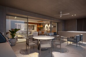 Ein modernes Interieur mit Essbereich, der Korbmöbel, eine Glastrennwand und einen Blick in eine Küche bietet.