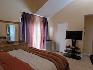A bedroom with a bed, a dresser, a television, and a door. - Shared Pool + Hot Tub • Indoor Fireplace (Los Angeles)