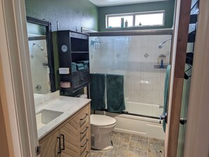 A bathroom with a shower, toilet, sink, and a cabinet with towels. - Shared Pool + Hot Tub • Indoor Fireplace (Los Angeles)
