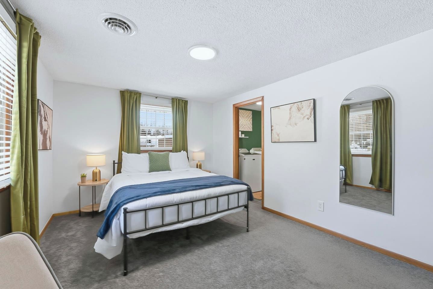A hotel room with a bed, two bedside tables with lamps, a mirror, and a view of the outside.