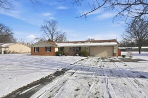 Ein Wohnhaus mit Garage, Auffahrt und einem mit Schnee bedeckten Rasen.