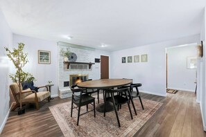 A dining area with a round table and chairs, a fireplace, and a plant. - Huntertown Haven |3 Bed 3 Ba Ranch Families & Pets (Huntertown)