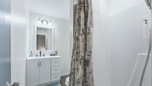 Ein Badezimmer mit Dusche, Waschbecken mit Spiegel und Toilette.