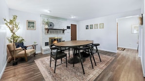 Ein modernes Wohnzimmer mit Kamin, einem Esstisch mit Stühlen, einer Couch und einer Topfpflanze.