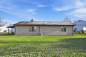 A single-story house with a flat roof, a covered porch, and a lawn with scattered leaves. - Huntertown Haven |3 Bed 3 Ba Ranch Families & Pets (Huntertown)