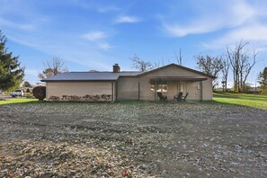 A single-story house with a garage, a covered porch with two chairs, and a gravel driveway. - Huntertown Haven |3 Bed 3 Ba Ranch Families & Pets (Huntertown)