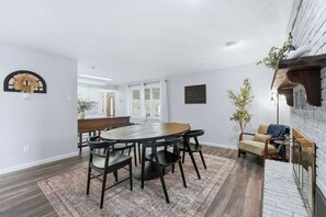 A dining area with a round table, chairs, and a bench. There is a rug on the floor, a wall-mounted clock, and a framed sign. - Huntertown Haven |3 Bed 3 Ba Ranch Families & Pets (Huntertown)