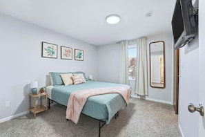 A bedroom with a bed, a bedside table, a mirror, and framed artwork on the wall. - Huntertown Haven |3 Bed 3 Ba Ranch Families & Pets (Huntertown)