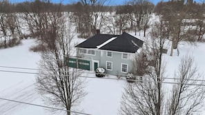 A two-story house with a dark roof and a green garage door, surrounded by snow-covered ground and leafless trees. - 2926 Smith Road House (Fort Wayne)