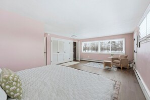 A bedroom with a bed, a chair, a window, and a closet. - 2926 Smith Road House (Fort Wayne)