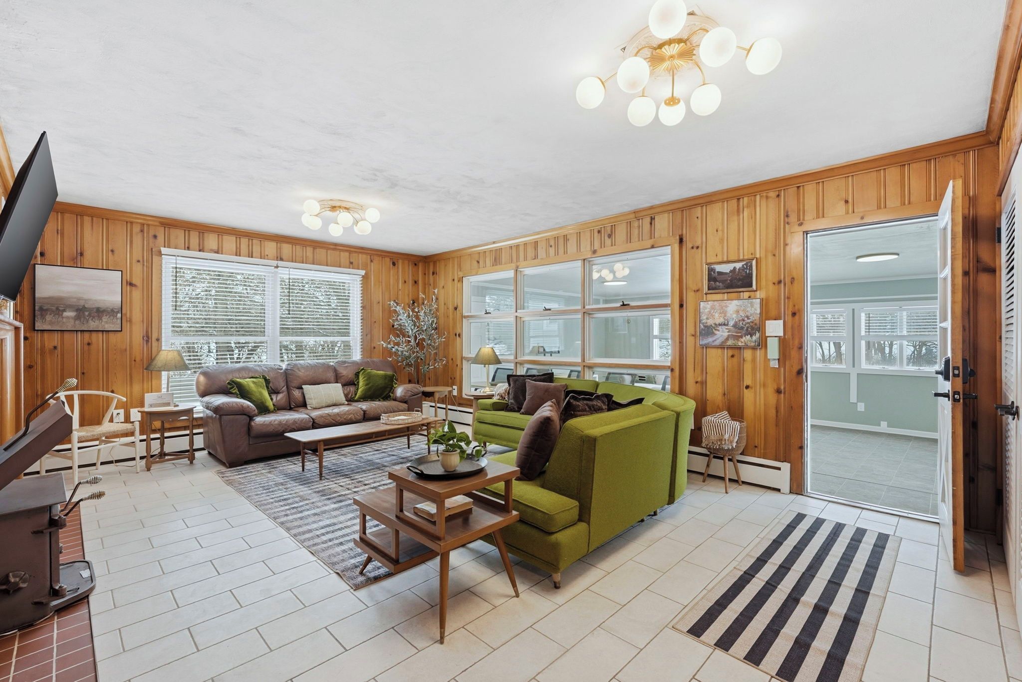 A living room with a brown leather sofa, a green sofa, a wooden coffee table, and a television.