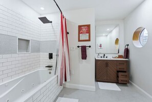 A modern bathroom with a white-tiled shower, a bathtub, and a vanity with a mirror. - Hoosier House! Massive 4 BD 2.5Ba for 12 TVs (Fort Wayne)