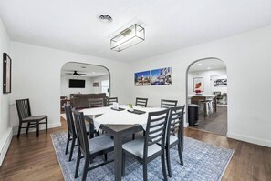 A dining area with a white table, dark chairs, and a blue rug. - Hoosier House! Massive 4 BD 2.5Ba for 12 TVs (Fort Wayne)