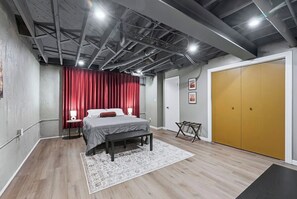 A bedroom with a bed, bedside tables, a bench, a wardrobe, and a door. - Hoosier House! Massive 4 BD 2.5Ba for 12 TVs (Fort Wayne)
