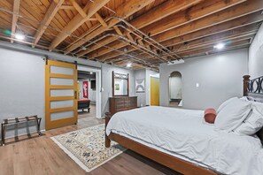 Une chambre à coucher avec un plafond en bois, un lit avec une literie blanche, une commode et un miroir.
