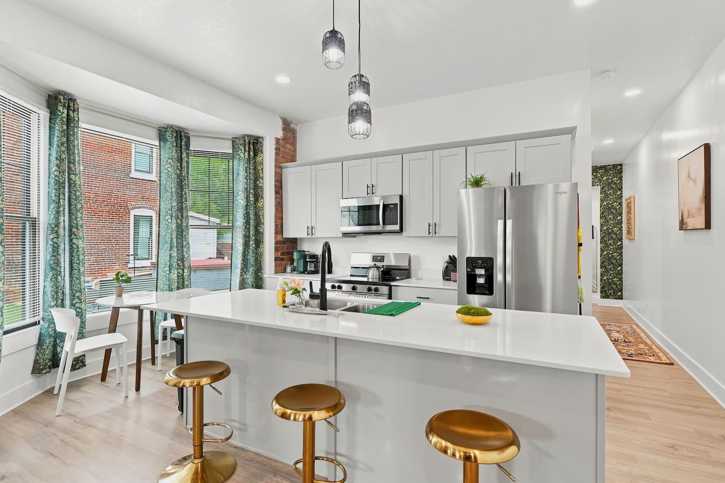 Una cocina moderna con una isla central, electrodomésticos de acero inoxidable y una zona de comedor con taburetes de bar.