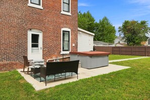 A backyard with a brick house, a covered patio, a grill, and a small shed. - 2BR | Tennis, Kitchen, PetsWelcome, Fenced Yard (Fort Wayne)
