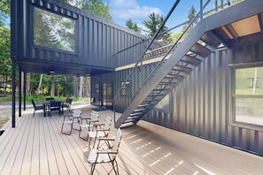 Una terraza de madera moderna, de varios niveles, con mobiliario exterior y una escalera.