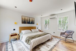 A bedroom with a bed, bedside tables, a chair, a painting, and two windows. - Unique Container Home | Rooftop Deck | Minutes to Mount Snow (West Dover)