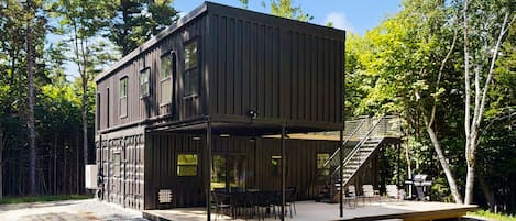 A modern two-story cabin with a covered patio and outdoor seating area.
