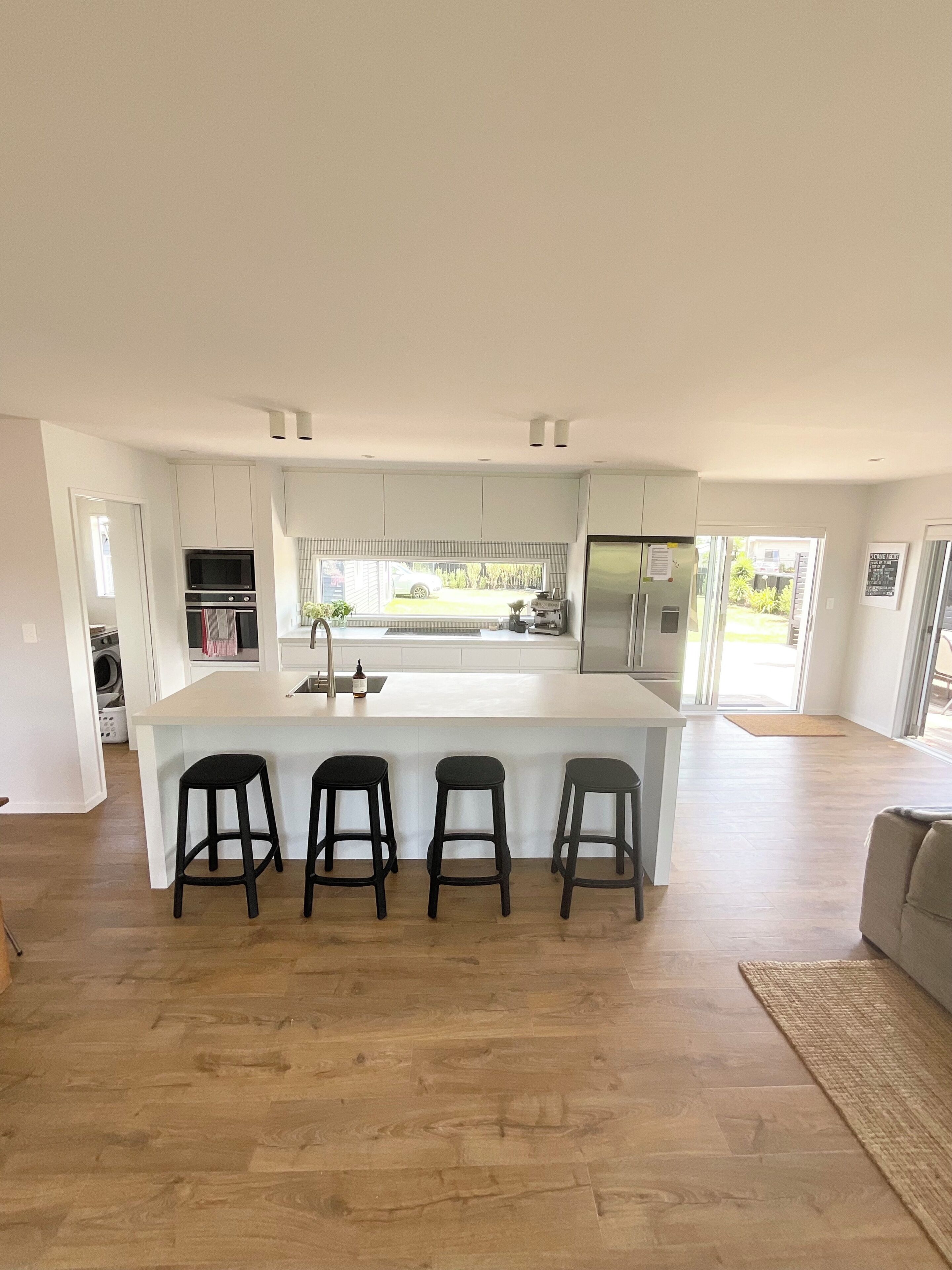 Una cocina moderna con una isla central, taburetes de bar y vistas al exterior.