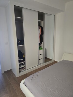 Une chambre à coucher avec un grand lit, une armoire à plusieurs compartiments et un miroir.
