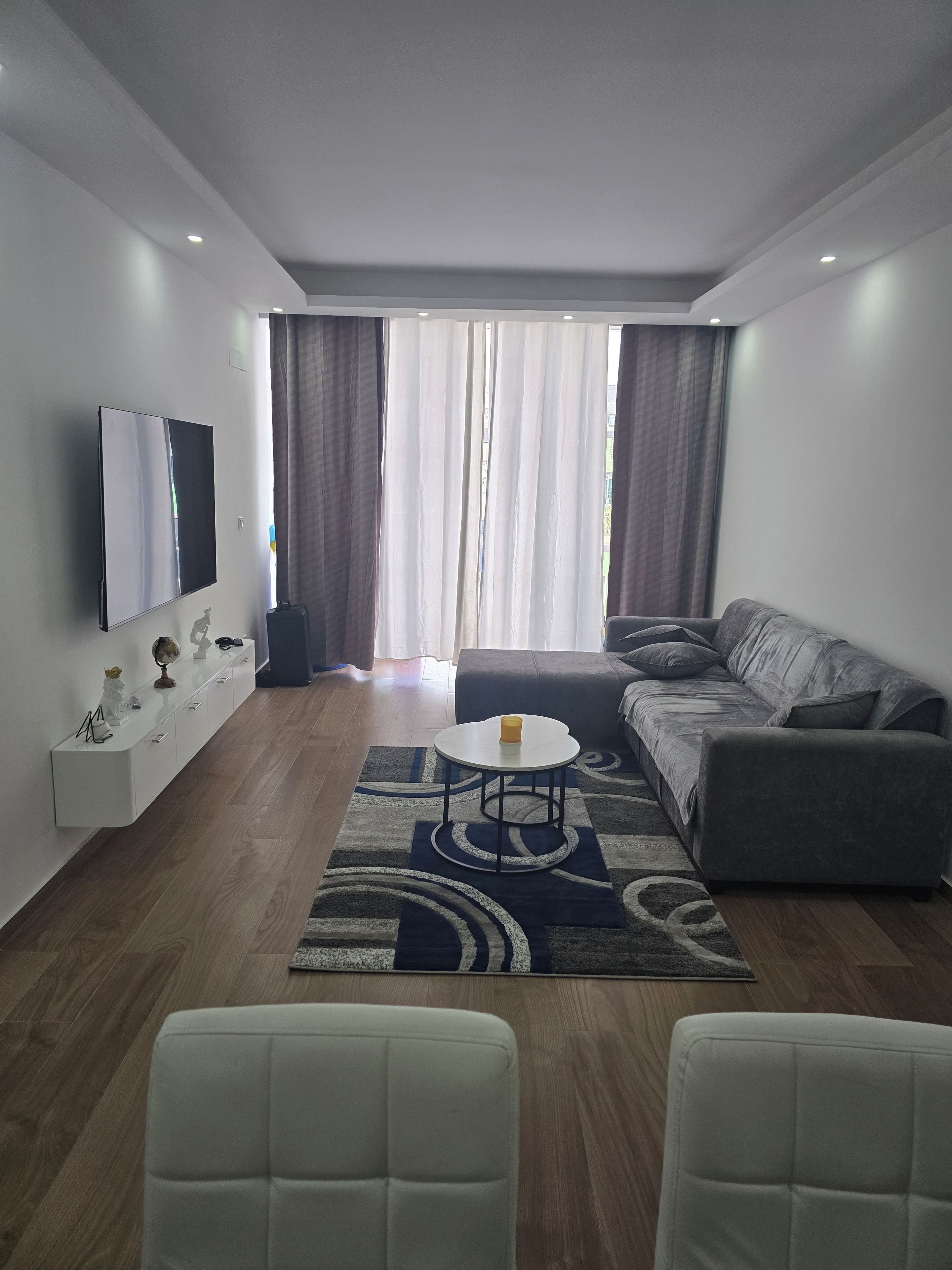 A modern living room with a sofa, a coffee table, and a TV mounted on the wall.