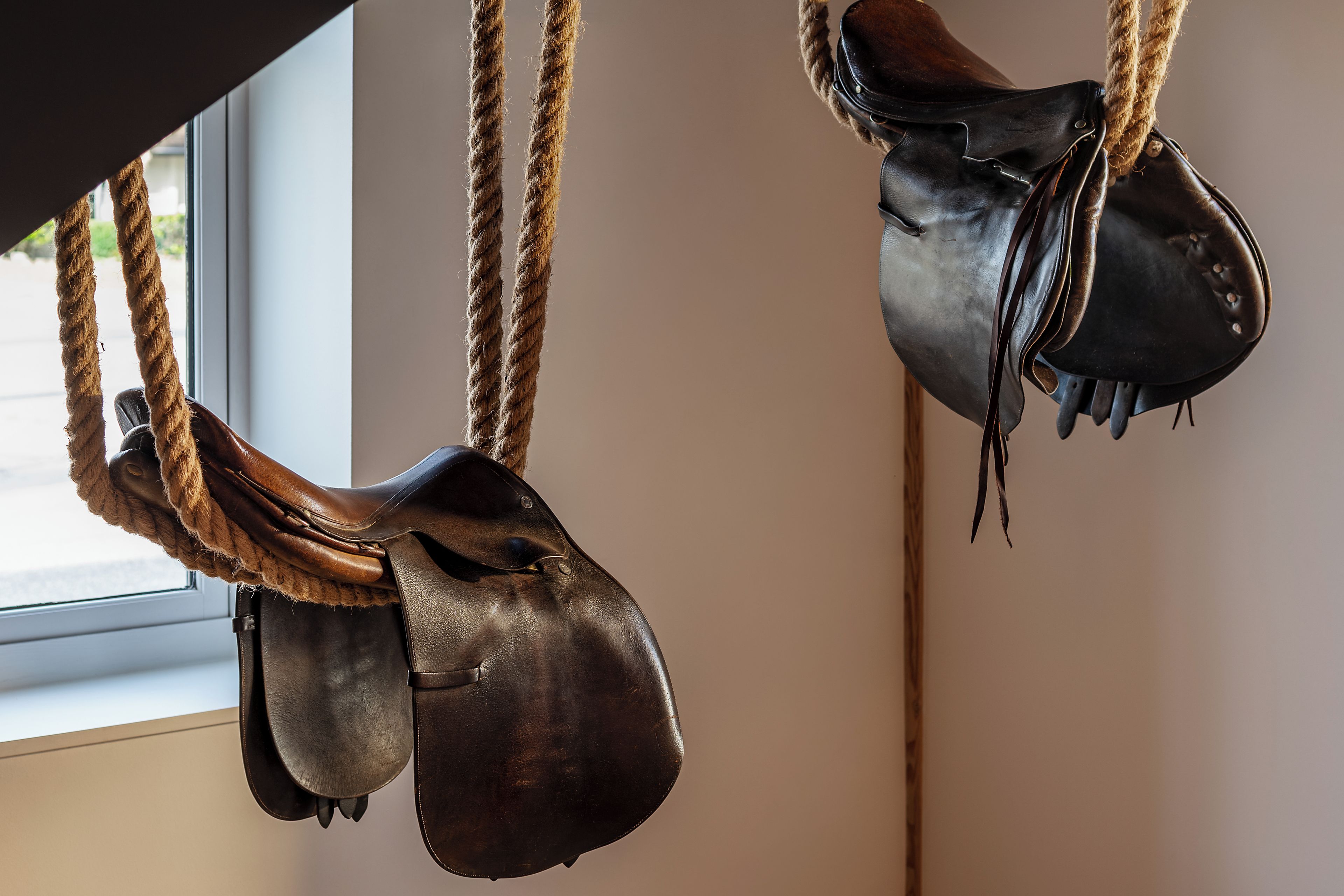 A pair of leather boots hanging by ropes.