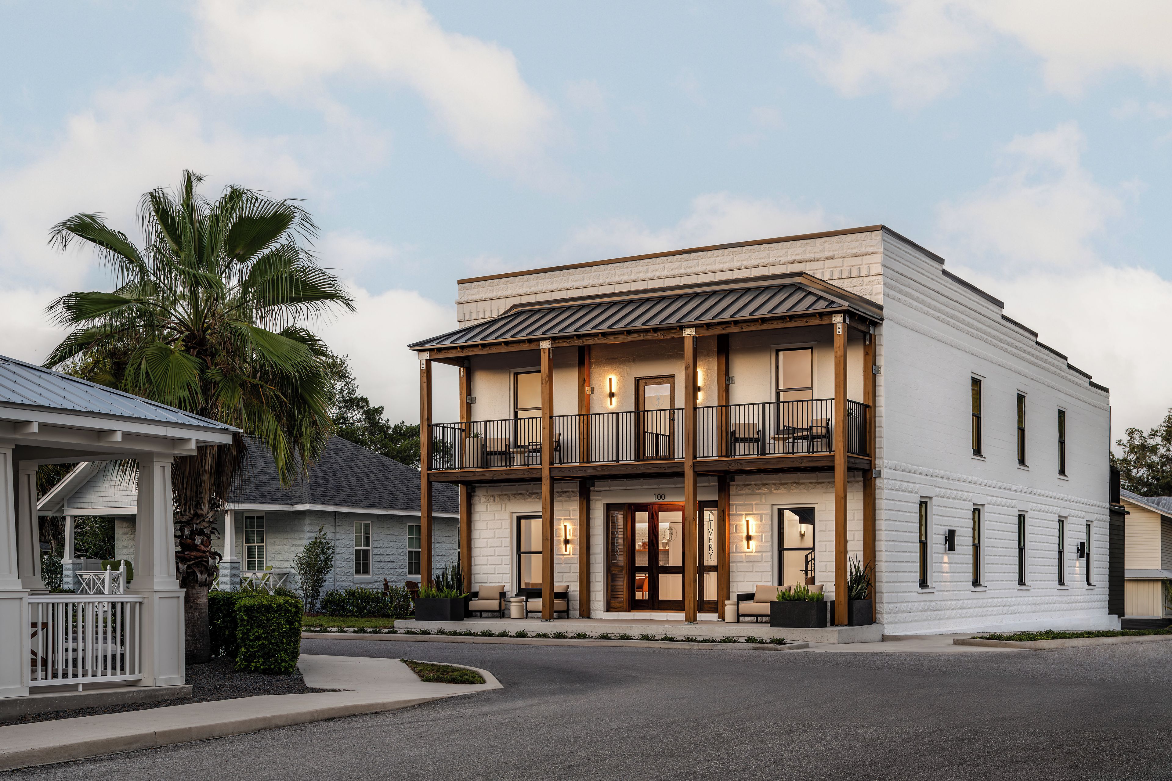 A two-story building with a balcony and a porch, featuring a brick facade and a flat roof.