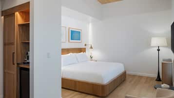 A hotel room with a bed, bedside table, lamp, and a wooden wardrobe.