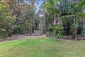 A grassy area with a fence, trees, and a concrete structure. - Sandy Paws 
Toogoom 
Beachfront (Toogoom)